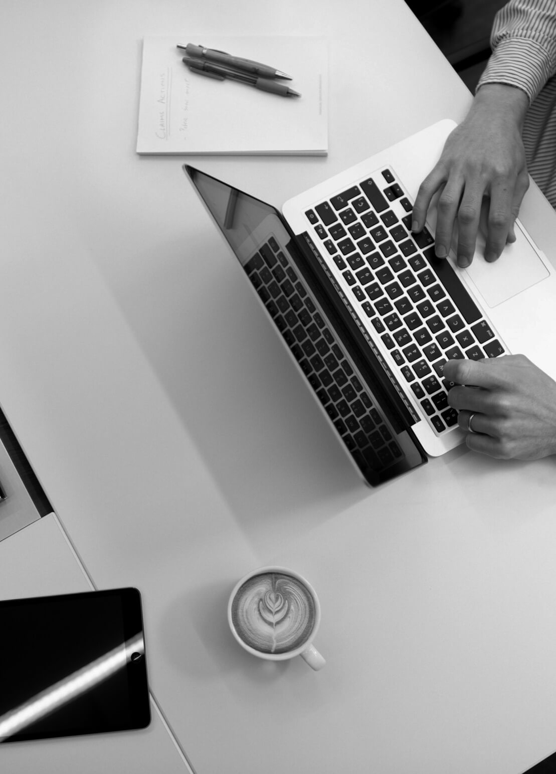 Work table with a computer, cup, tablet, notebook and pen